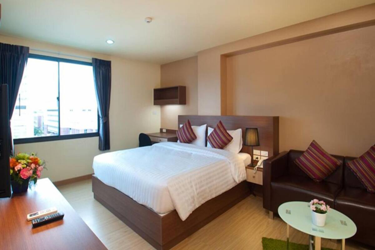 Una habitación de hotel con una cama grande, un escritorio, un sofá y una pequeña mesa con flores.