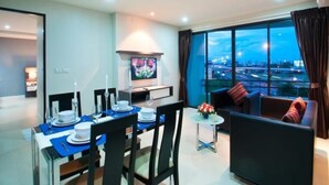 Una sala de estar moderna con comedor, televisor de pantalla plana y un amplio ventanal con vista a la ciudad.