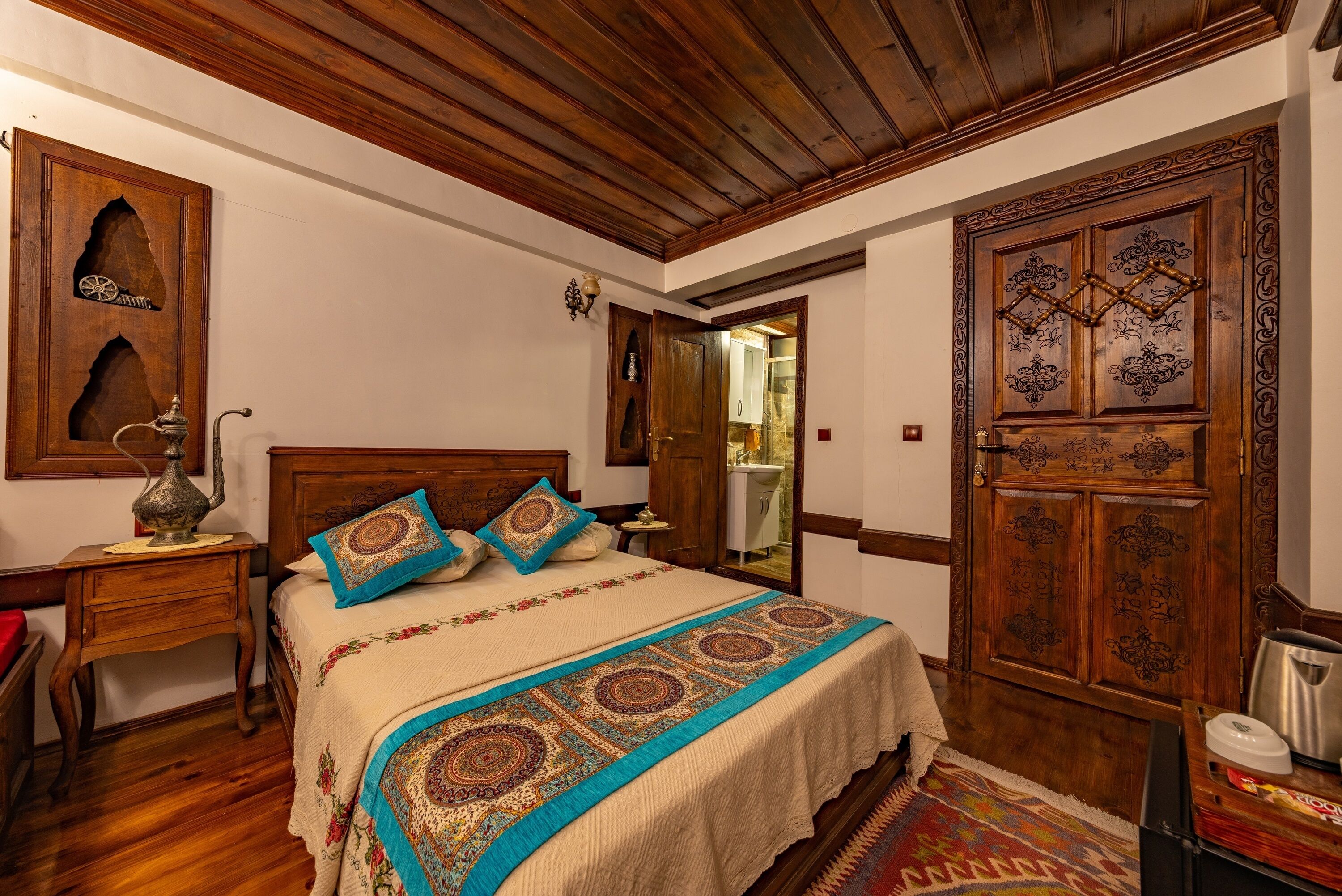 A traditional room with a wooden bed, a nightstand, a decorative lamp, and a large wooden wardrobe.