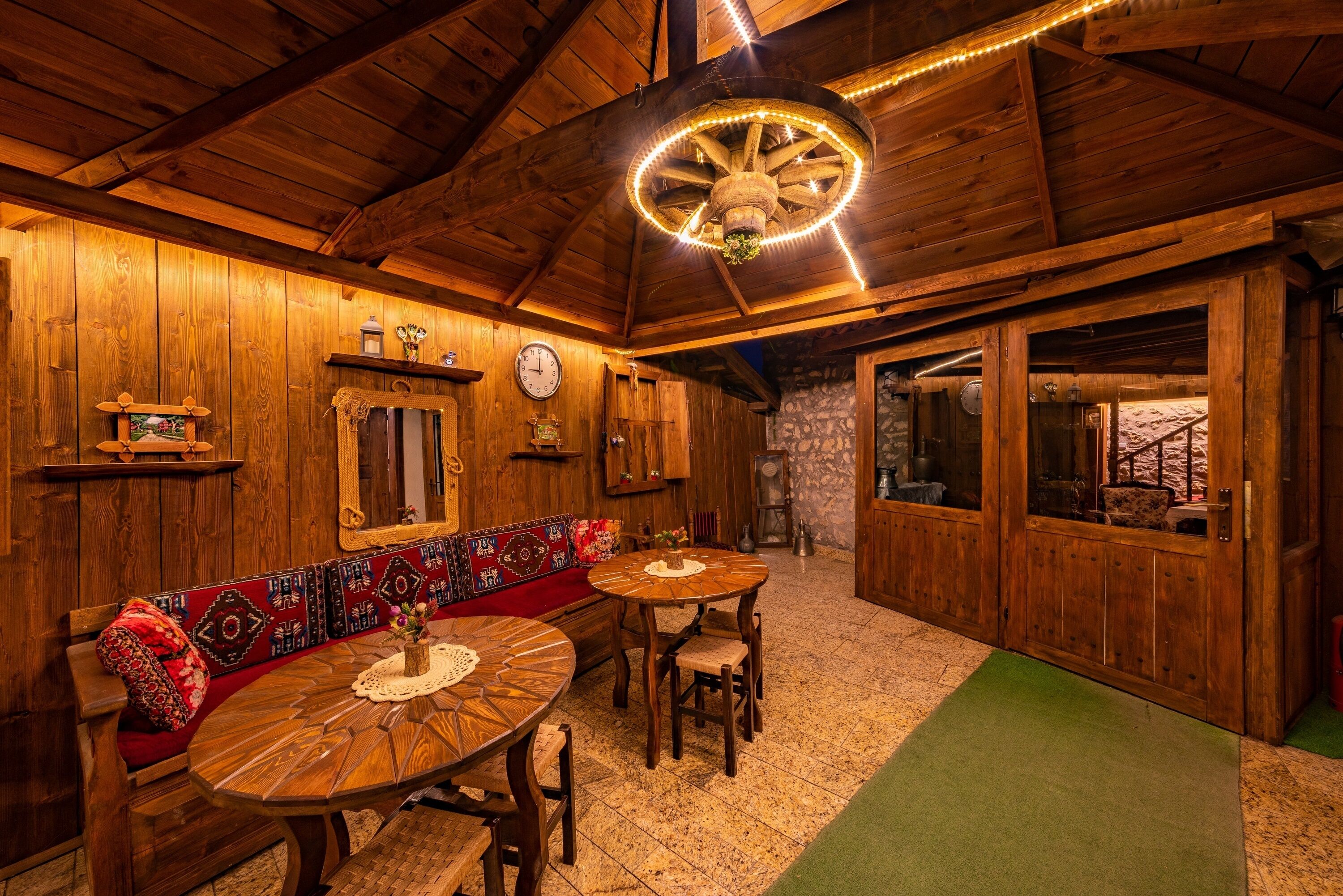 A wooden interior with a round table, benches, and a decorative ceiling light.