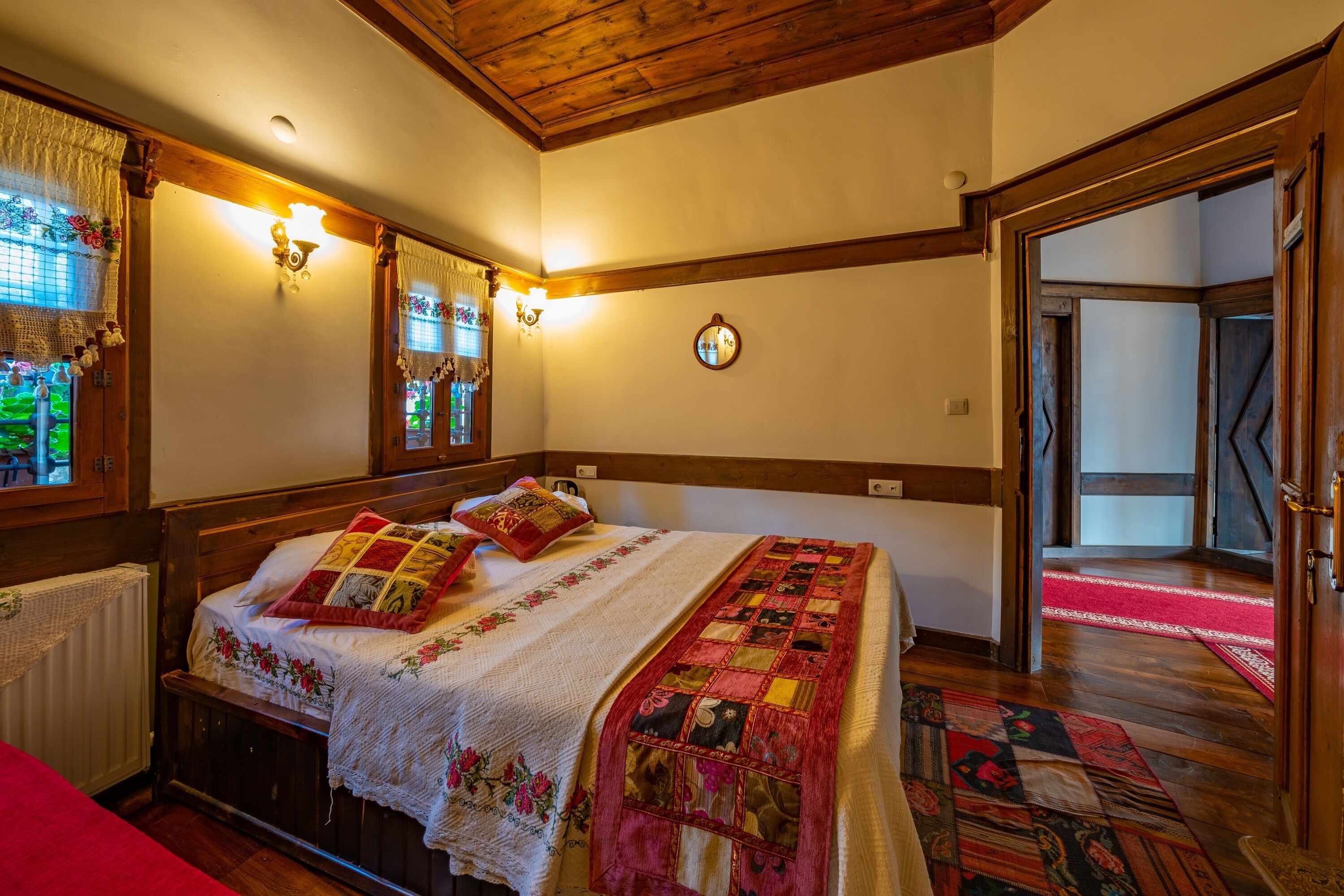 A cozy bedroom with a wooden bed, a quilt, and a mirror on the wall.