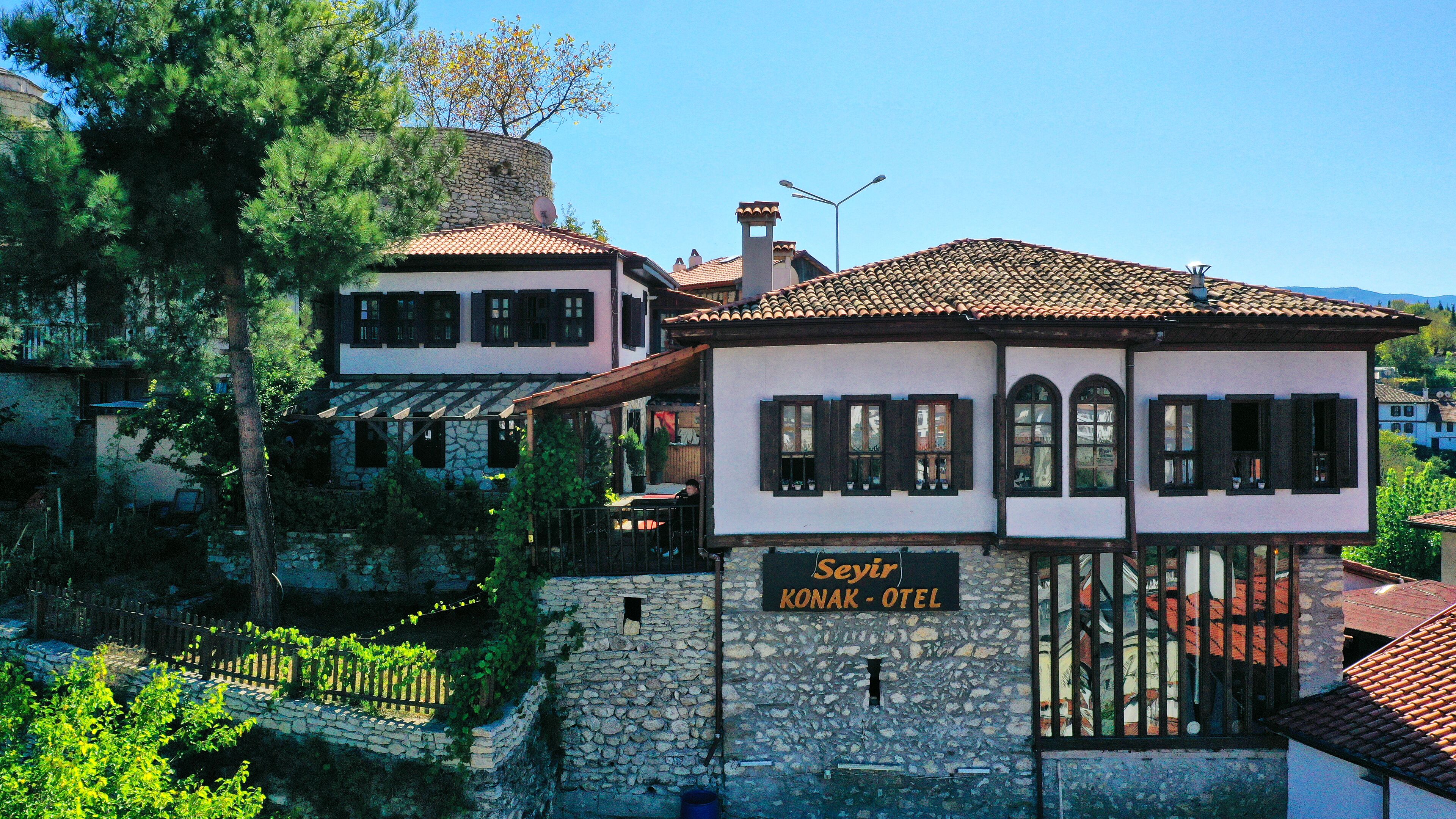 A traditional building with a stone facade, a sign for 'Seyr Konak - Hotel', and a view of the surrounding area.