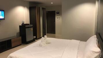 Quarto de hotel com uma cama grande, televisão montada na parede, minibar e porta que dá para outro quarto.