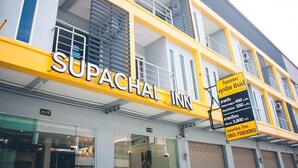 Un hotel chiamato Supachai Inn, con facciata gialla, diversi balconi e una targa con i recapiti.
