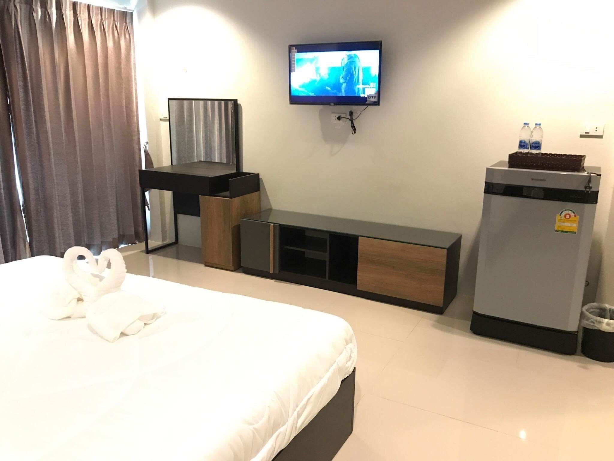 Une chambre d’hôtel équipée d’un lit, d’un téléviseur fixé au mur, d’un bureau et d’un réfrigérateur.