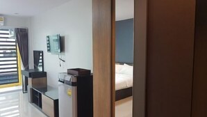 Una camera d'albergo con un letto, una scrivania, una sedia, una televisione e una finestra con tende.