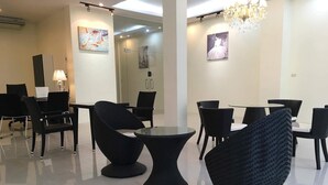 Zona pranzo moderna con sedie e tavoli neri, un lampadario e opere d'arte alle pareti.