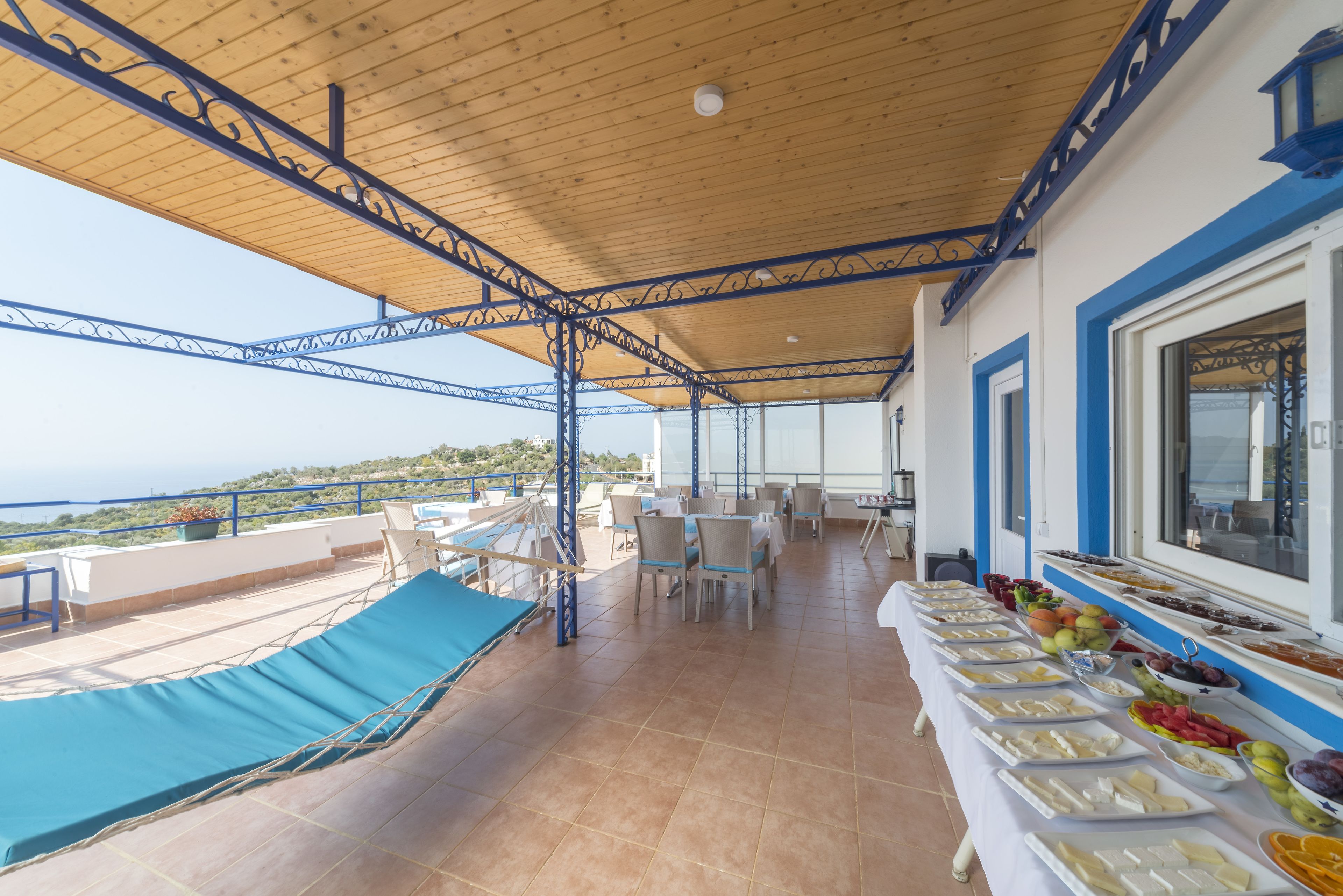 A covered outdoor dining area with a buffet table, chairs, and a view of the sea.