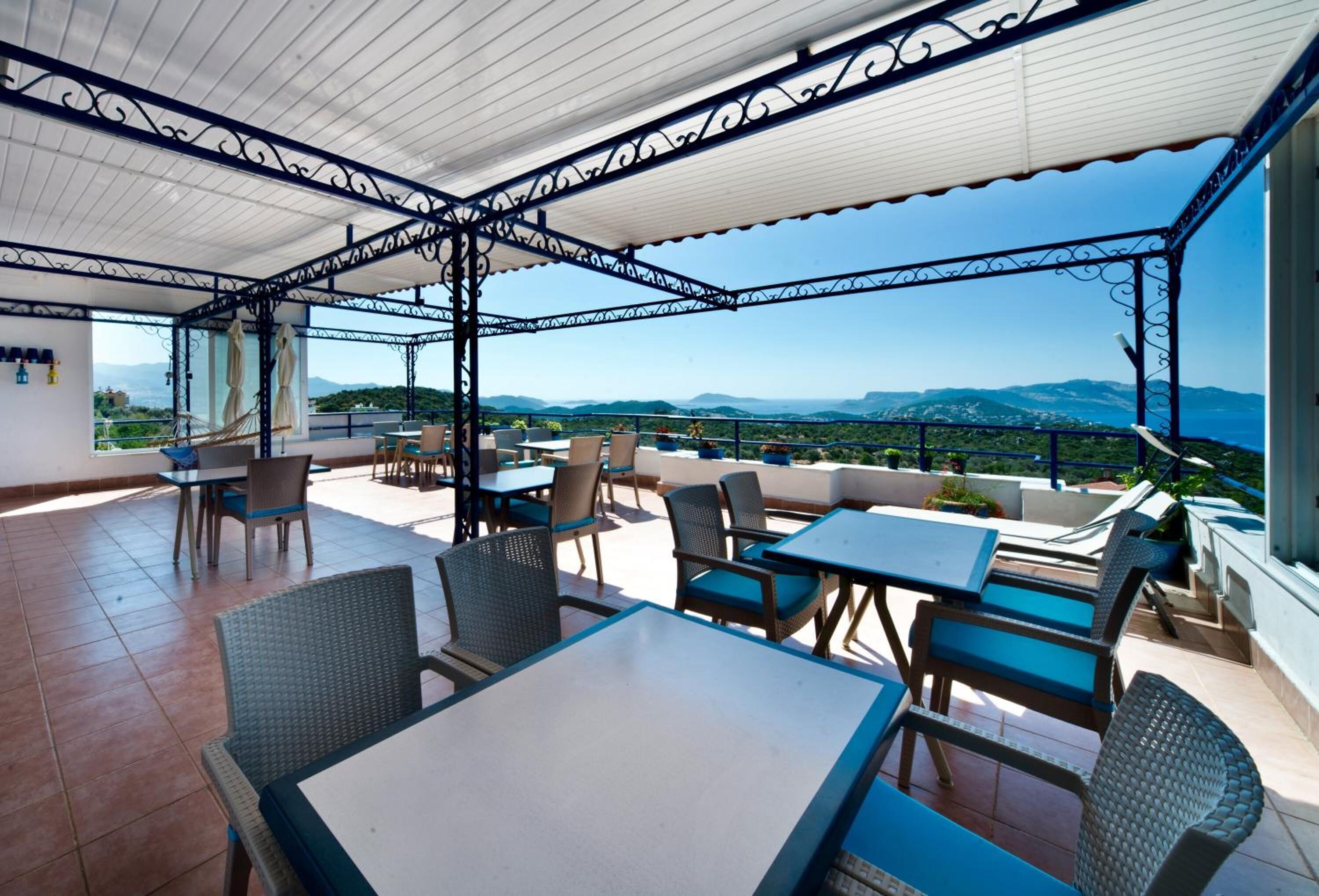Una terraza al aire libre con mesas y sillas, vistas al paisaje y una estructura de pérgola.