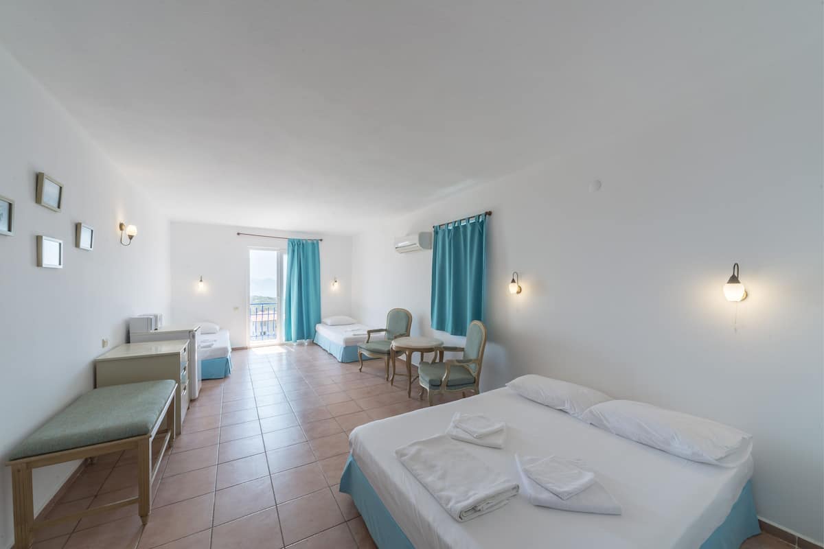 A hotel room with a bed, a desk, a chair, a small table, and a window with curtains.