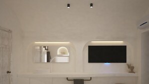 Un bany modern amb un mirall gran, una televisió de pantalla plana i un lavabo amb portaToalles.