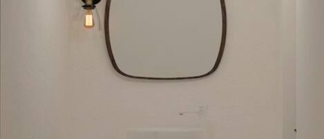 Un baño moderno con una bañera independiente, un lavamanos fijado a la pared y un perchero para toallas.