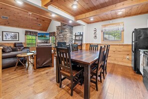 Un coin repas avec une table et des chaises en bois, une cheminée en pierre et une vue sur l’extérieur.