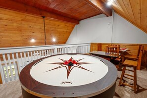 A room with a wooden ceiling, a round table with a star design, and a white railing.