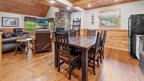 Ein gemütliches Blockhaus-Interieur mit Essbereich, Kamin aus Stein und Küche.