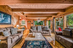 A wooden interior with a sofa set, a coffee table, and a dining area. - Bearly Hidden Ridge 5 Bedroom Cabin by RedAwning (Gatlinburg)