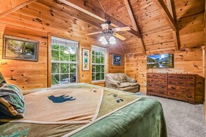 A wooden cabin bedroom with a bed, a chair, a dresser, and two windows. - Bearly Hidden Ridge 5 Bedroom Cabin by RedAwning (Gatlinburg)