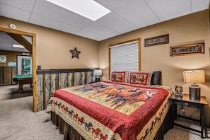 A hotel room with a large bed, a desk, a lamp, and a window with blinds. - Bearly Hidden Ridge 5 Bedroom Cabin by RedAwning (Gatlinburg)