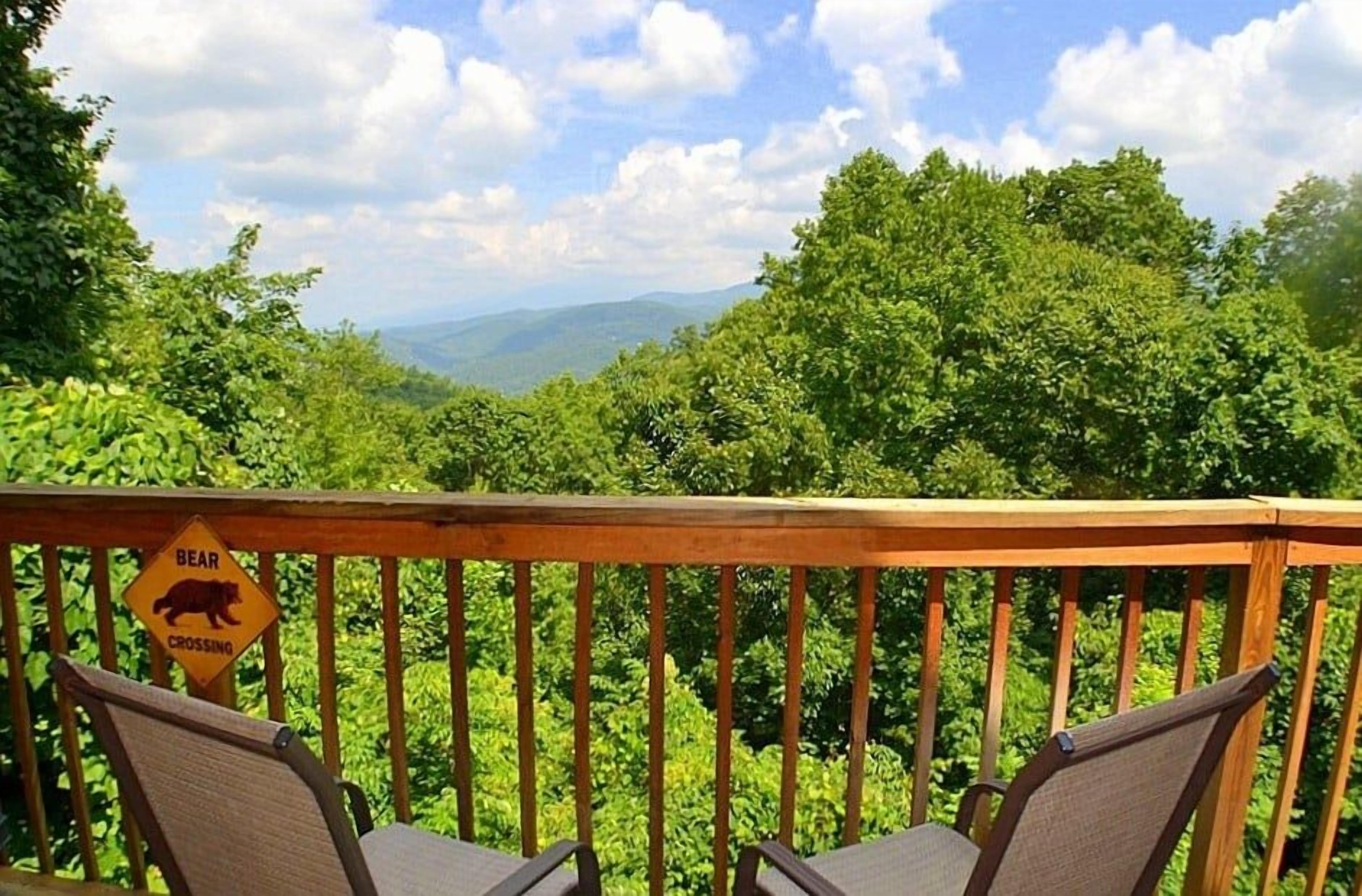 Eine Terrasse mit einem Schild, das einen Bären zeigt, mit Blick auf eine bewaldete Landschaft.