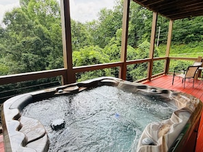 Un bain à remous sur une terrasse en bois, avec vue sur une végétation luxuriante.