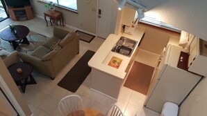 Un espacio habitable compacto con kitchenette, un sofá, una mesa de comedor y una pequeña zona de televisión.