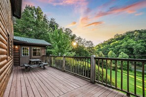 A wooden deck with a picnic table and a small cabin with a metal roof. - The Ranch Cabin on 6 Secluded Acres in the Great Smoky Mountains by RedAwning (Sevierville)