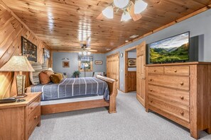 A bedroom with a bed, wooden dresser, and a television on a wall. - The Ranch Cabin on 6 Secluded Acres in the Great Smoky Mountains by RedAwning (Sevierville)
