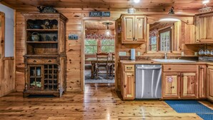A wooden cabin interior with a kitchen area, a dining table, and a sign reading "Apple Farm". - The Ranch Cabin on 6 Secluded Acres in the Great Smoky Mountains by RedAwning (Sevierville)