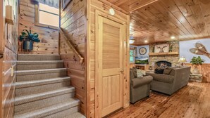 A wooden interior with a staircase, a fireplace, and a sofa. - The Ranch Cabin on 6 Secluded Acres in the Great Smoky Mountains by RedAwning (Sevierville)
