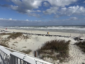 En strand med sandet bund, et træhegn og en klar himmel.