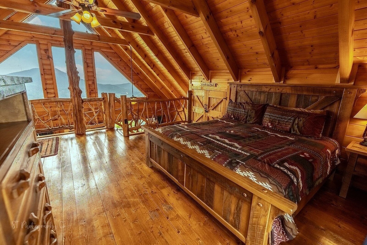 Une chambre à coucher aménagée dans les combles, avec un grand lit, des poutres en bois et une vue sur les montagnes.