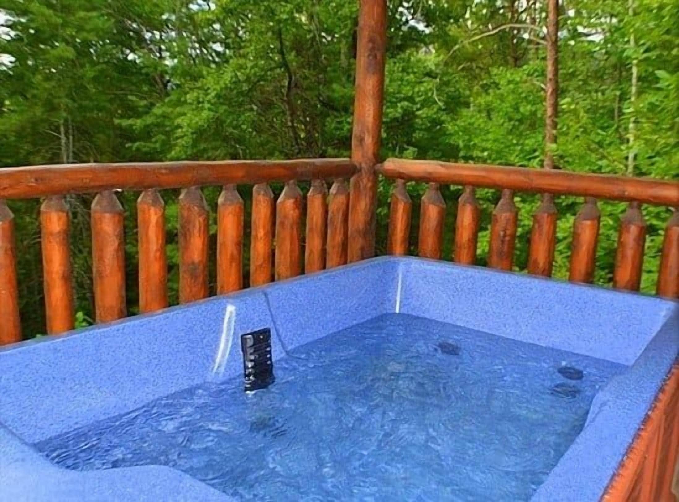 A hot tub with a wooden deck and a metal railing.