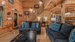 Een gezellig cabin interieur met houten wanden, een trap, een zithoek met twee banken, een salontafel en een keuken.