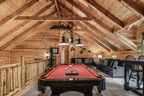 Un intérieur en bois comprenant une table de billard, un canapé et une table à manger.