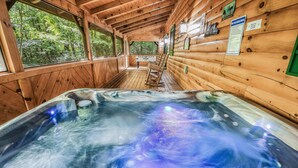 Een houten chalet met een bubbelbad, houten wanden en uitzicht op het bos.