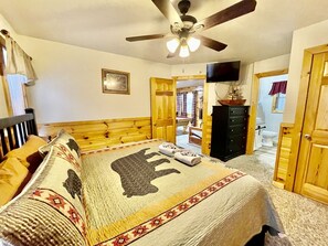 A bedroom with a bed, a ceiling fan, a television, and a wooden dresser. - Picture Perfect 2 Bedroom Cabin by RedAwning (Sevierville)