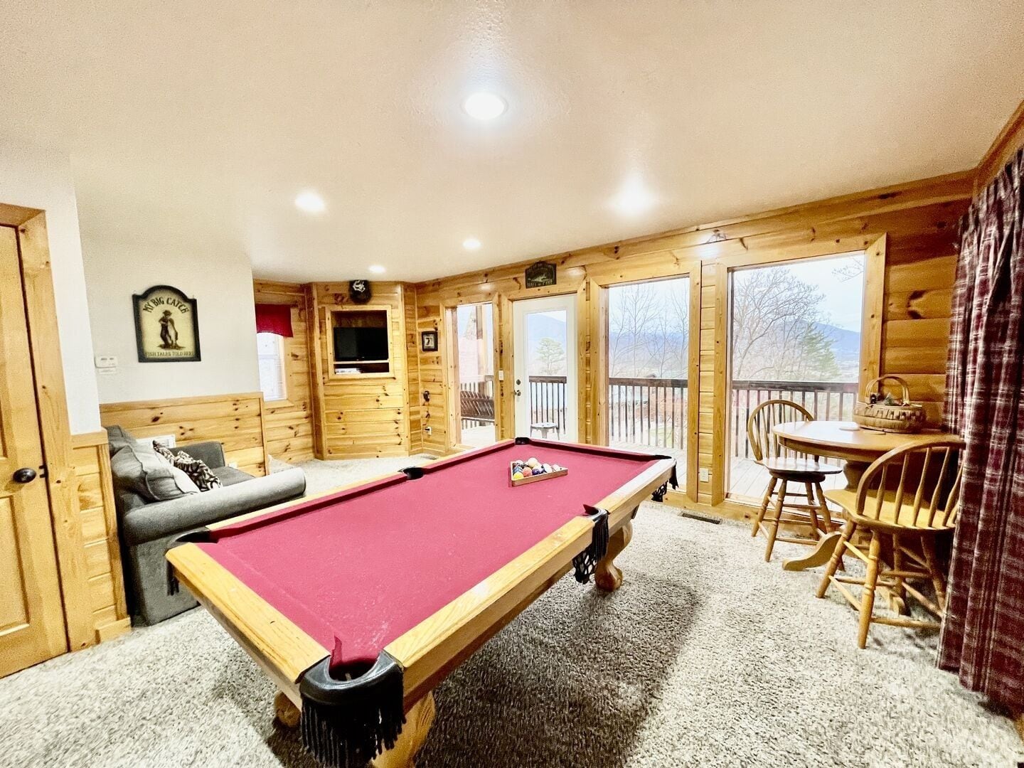 A pool table in a room with wooden walls and a sofa.