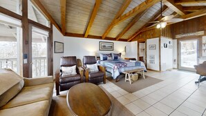 Una habitación acogedora con una cama, dos sillones de cuero, una mesa de madera y un ventilador de techo.