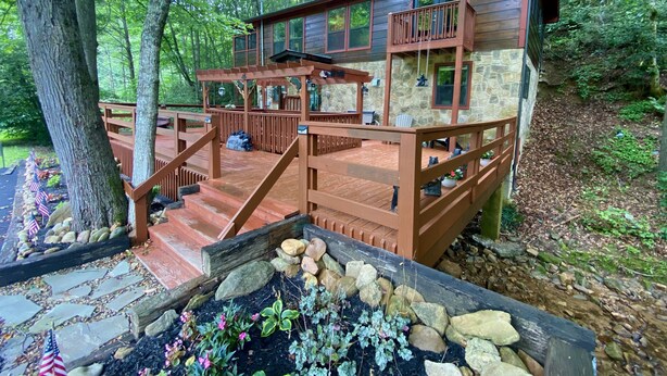 Une cabane dotée d’une terrasse en bois, de murs en pierre et d’un chemin en pierre menant à l’entrée.
