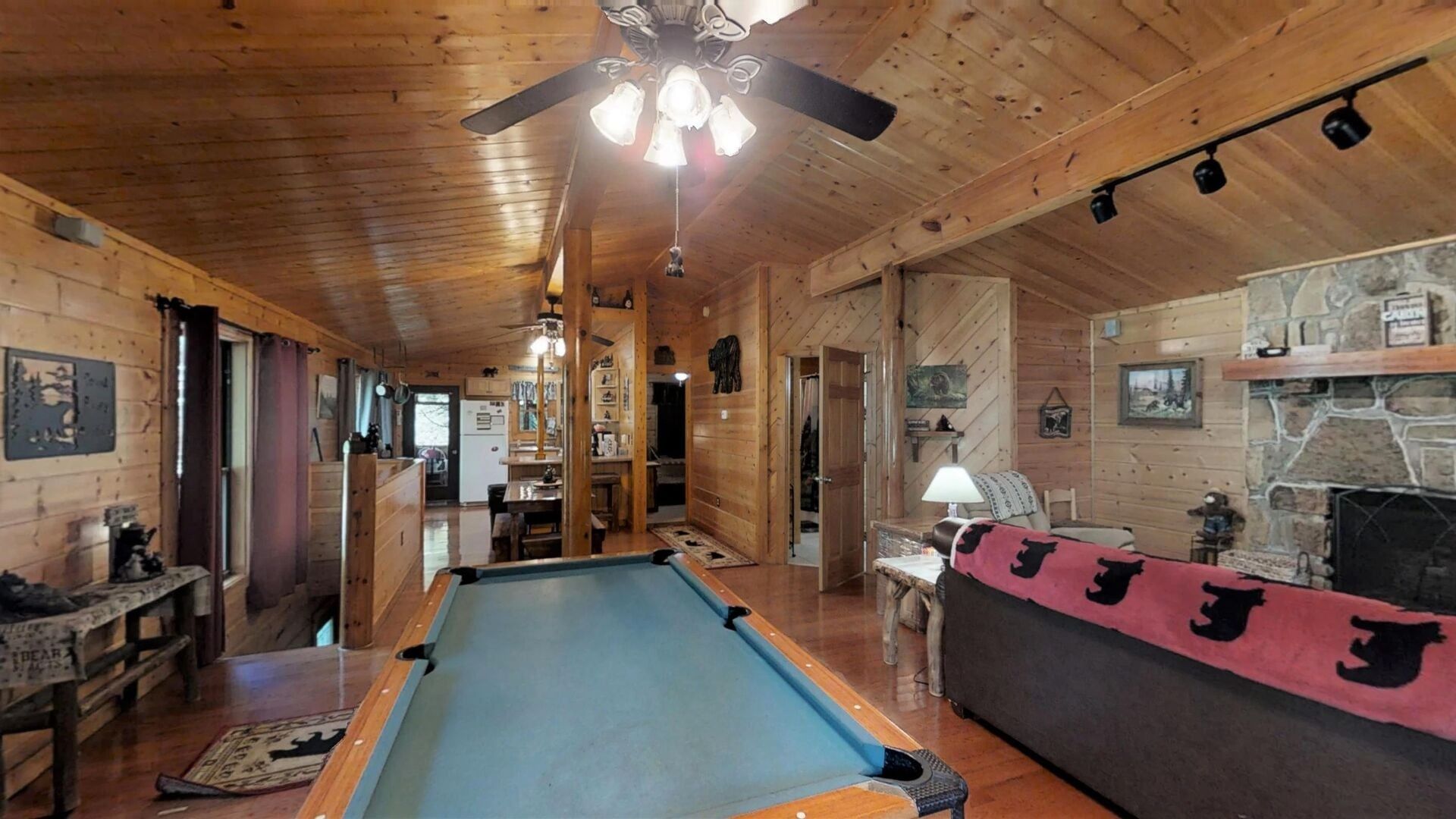 A wooden interior with a pool table, a couch, and a fireplace.
