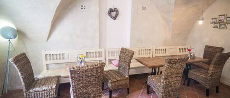 A dining area with wicker chairs and a bench, a table, and a wall-mounted heart decoration.