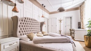 Un dormitorio con una cama grande, paredes blancas e iluminación colgante.
