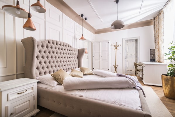 Un dormitorio con una cama grande, paredes blancas e iluminación colgante.