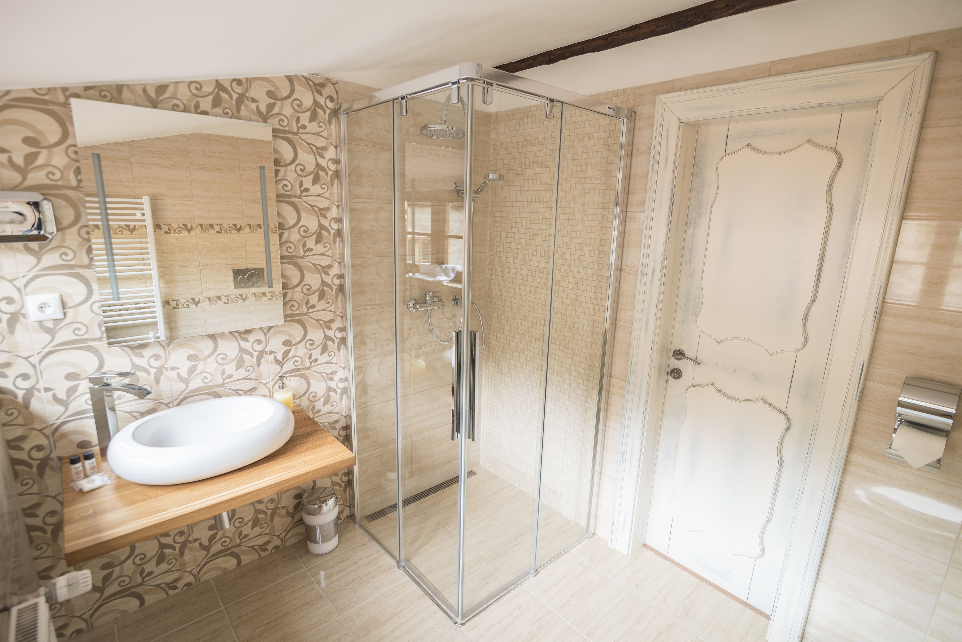 A modern bathroom with a glass-enclosed shower, a wooden vanity, and a large mirror.