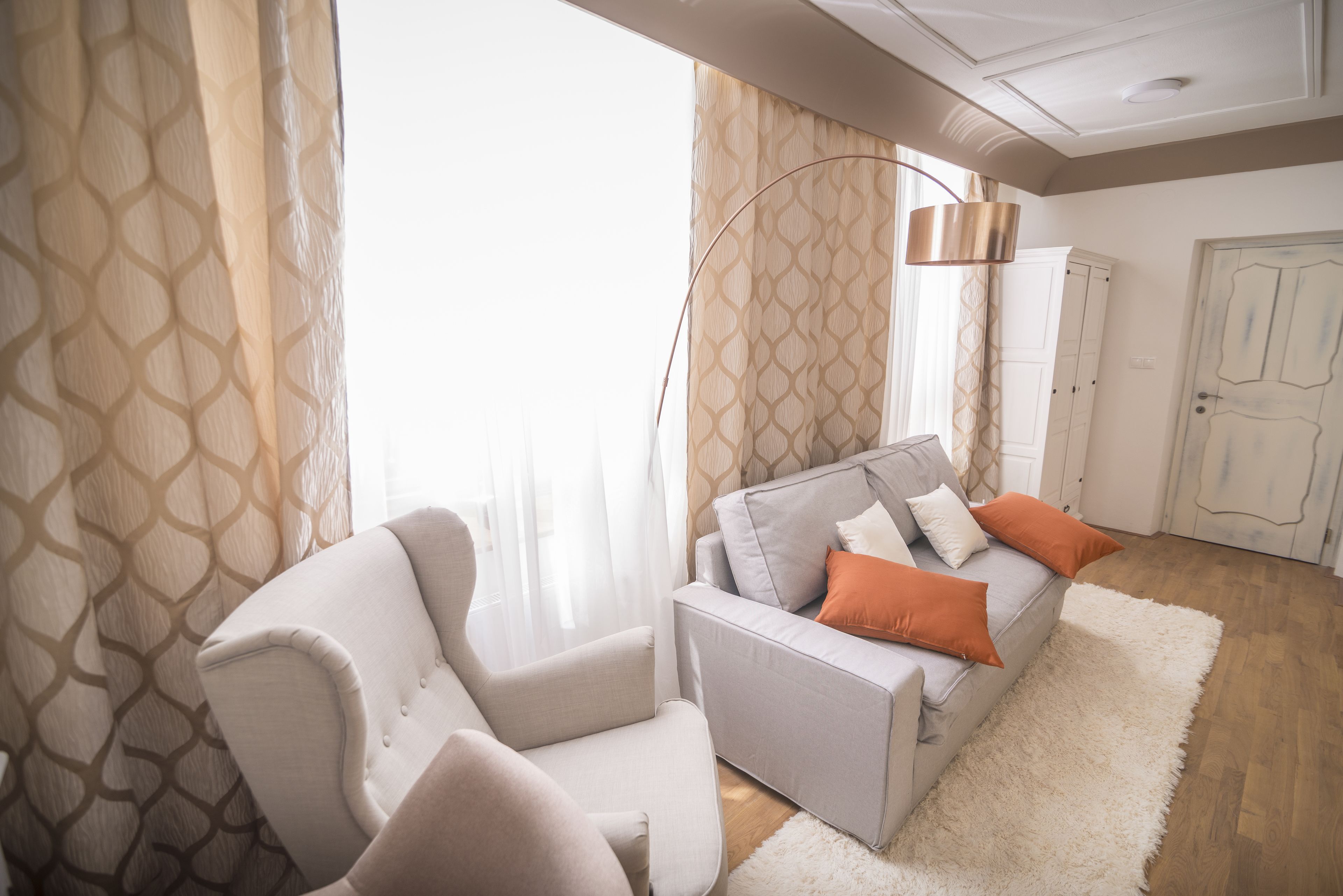 A modern living room with a sofa, armchair, and floor lamp.