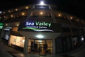 Un edificio con un letrero que dice 'Sea Valley Furnished Suites', indicando un hotel o alojamiento.