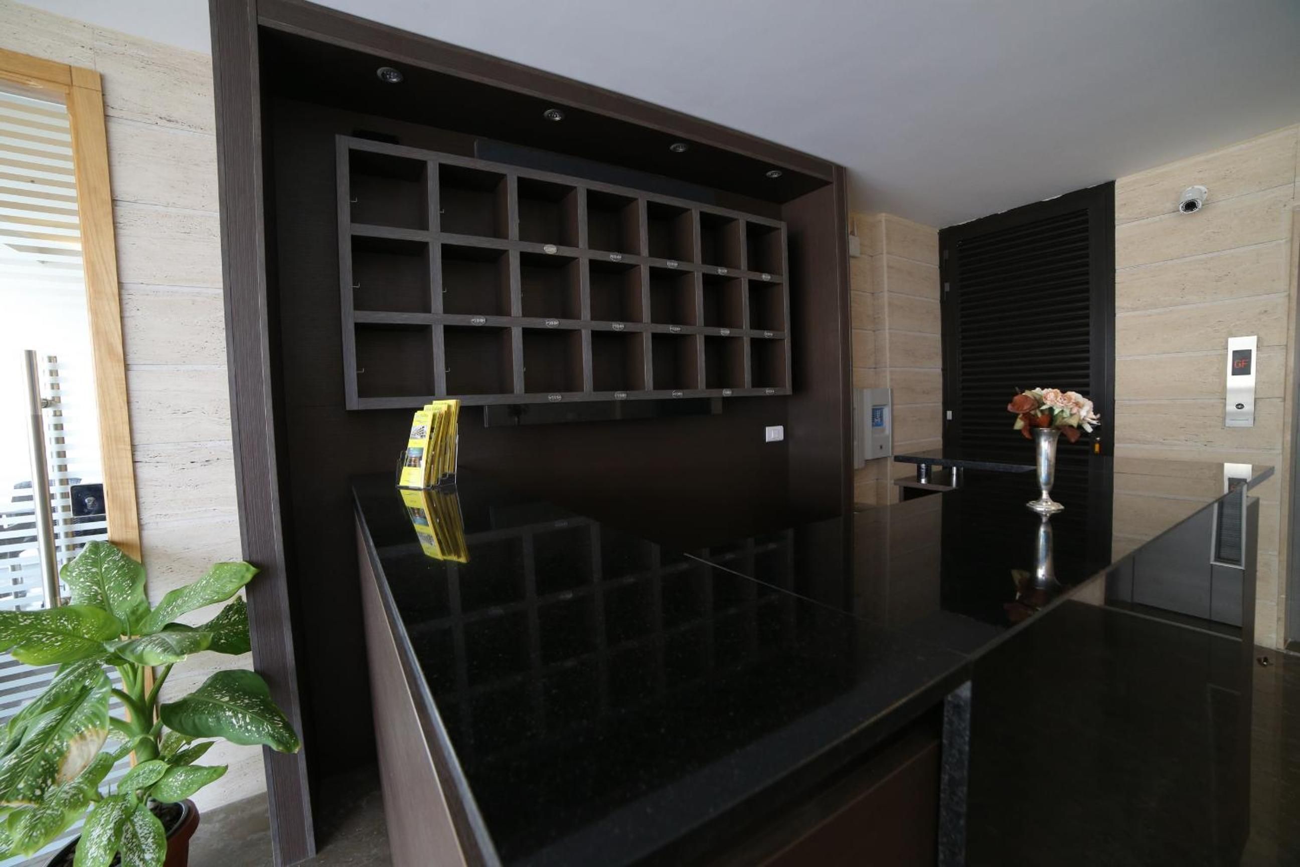 Una cuina moderna amb taulell negre, forn integrat i una gerra decorativa amb flors.