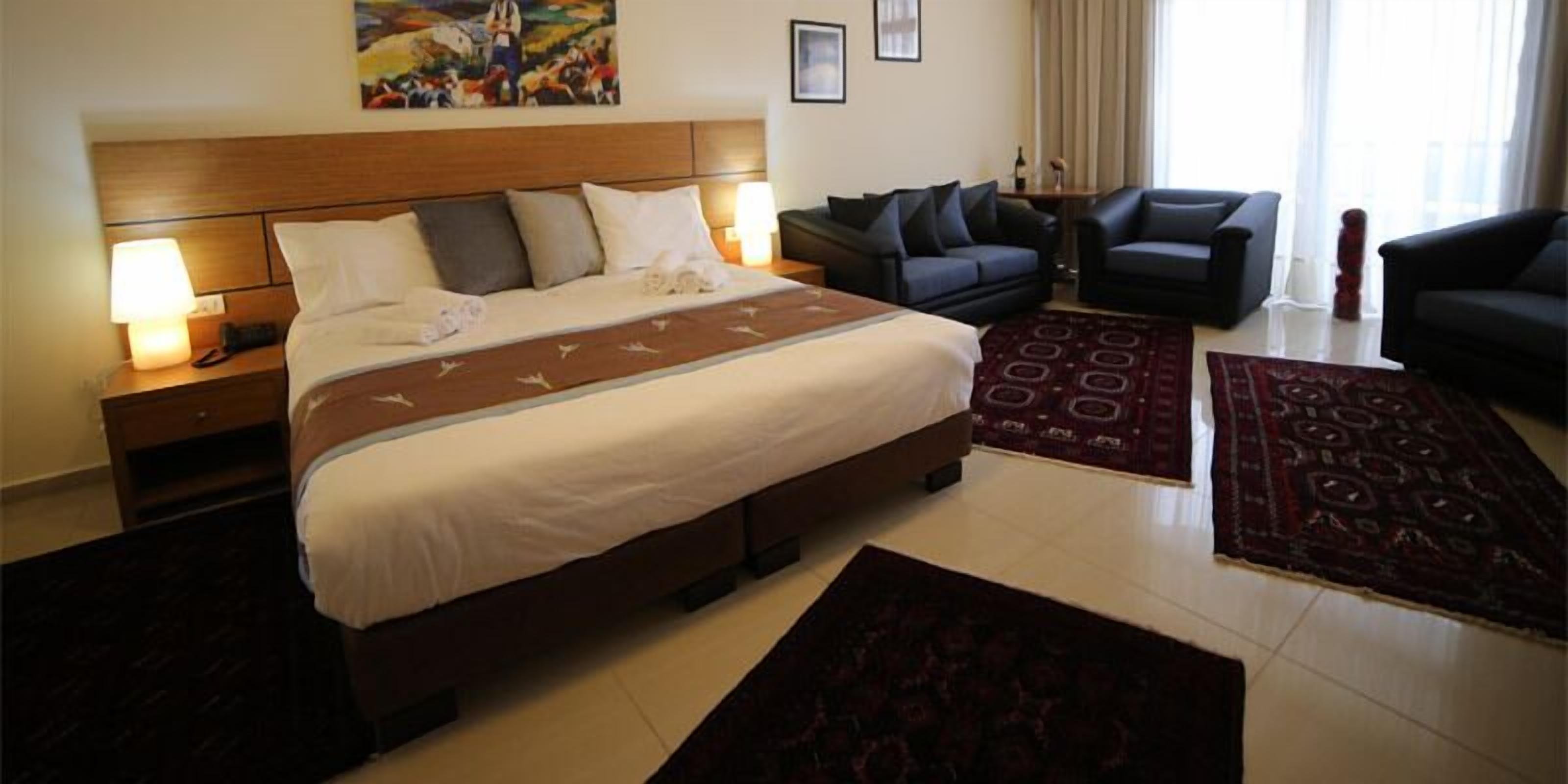 Ein Hotelzimmer mit einem großen Bett, einem Sofa, einem Couchtisch und einem gemusterten Teppich.