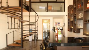 Een modern interieur met een spiltrap, een eetgedeelte en een bar met flessenkasten.