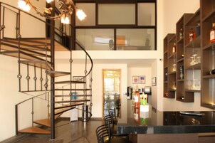 Un interior moderno con una escalera de caracol, un comedor y una zona de bar con estantes llenos de botellas.